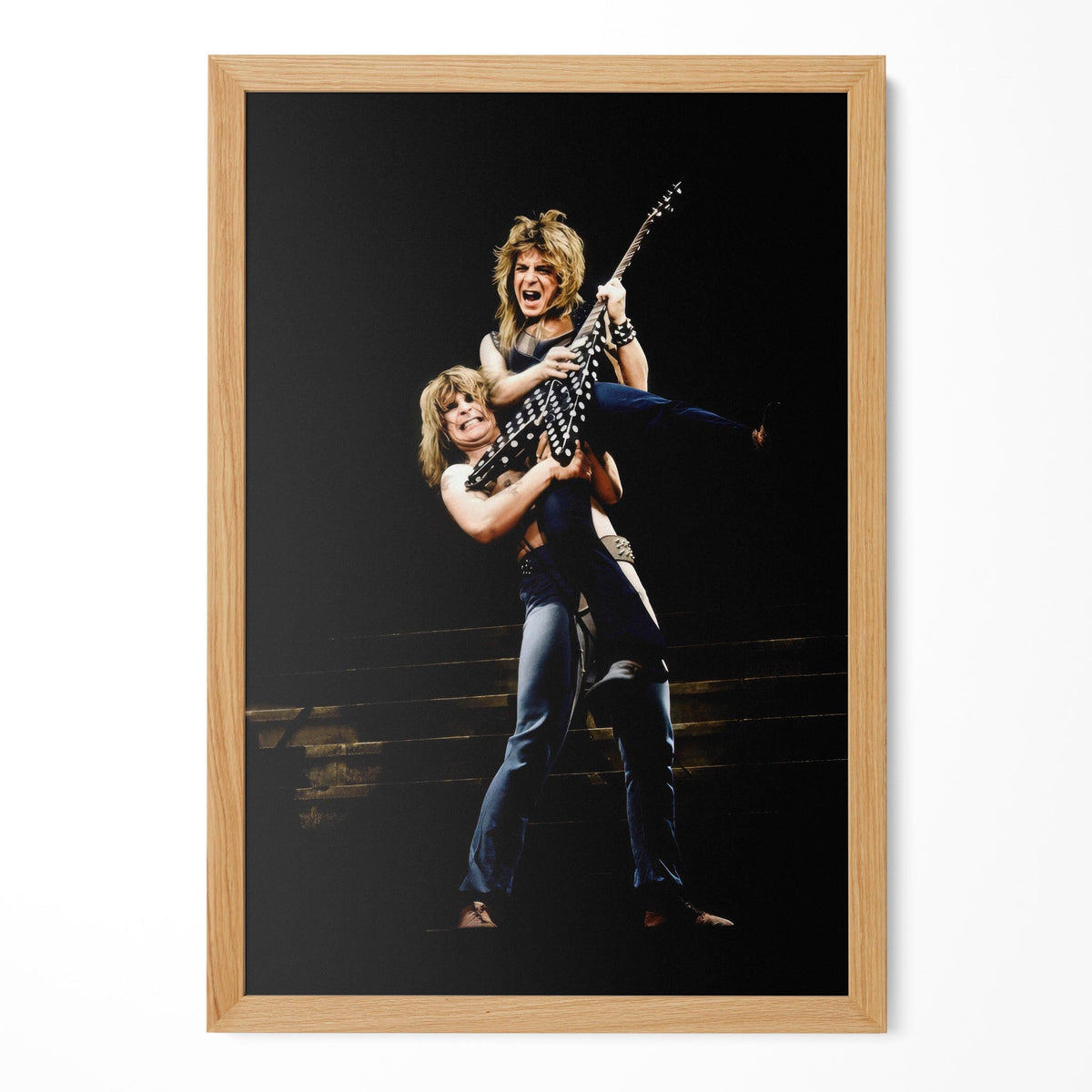 Restored 1982 concert print of Randy Rhoads hanging in a natural oak frame on a plain wall