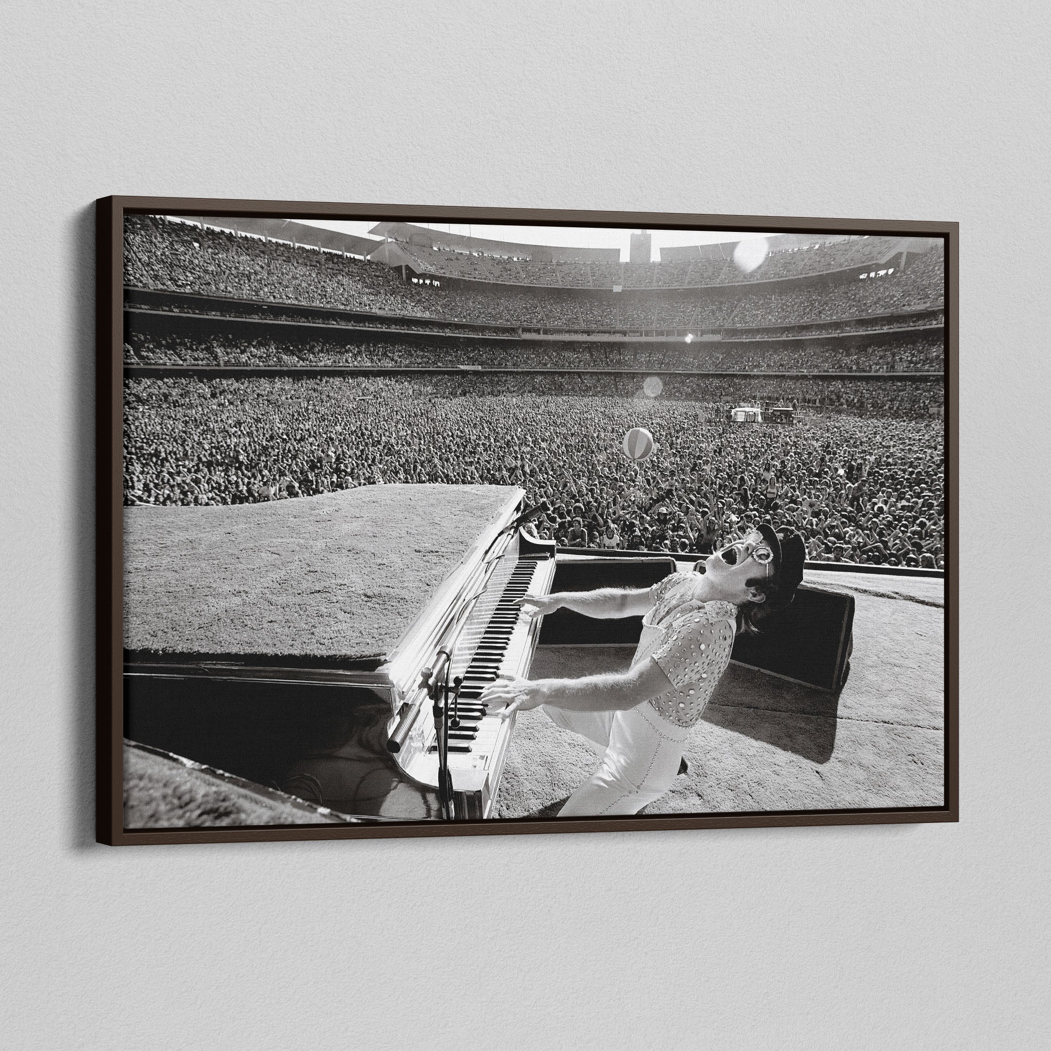 Angled view of the Elton John 1975 black and white canvas in a sophisticated dark walnut floating frame.