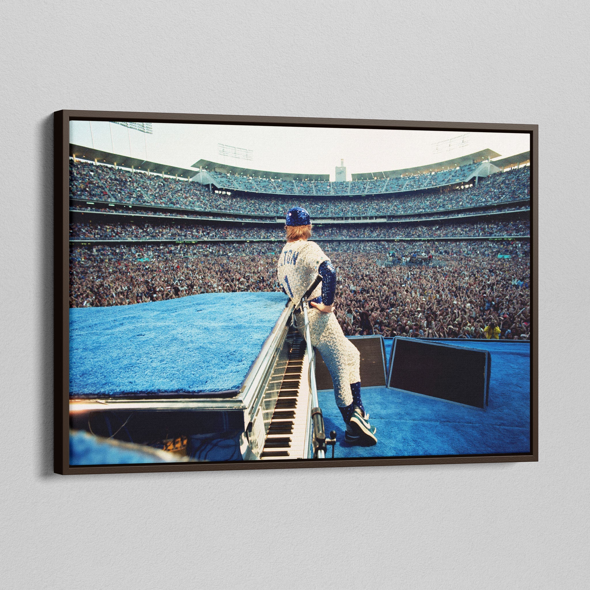 Angled view of the Elton John 1975 colorized canvas in a sophisticated dark walnut floating frame.