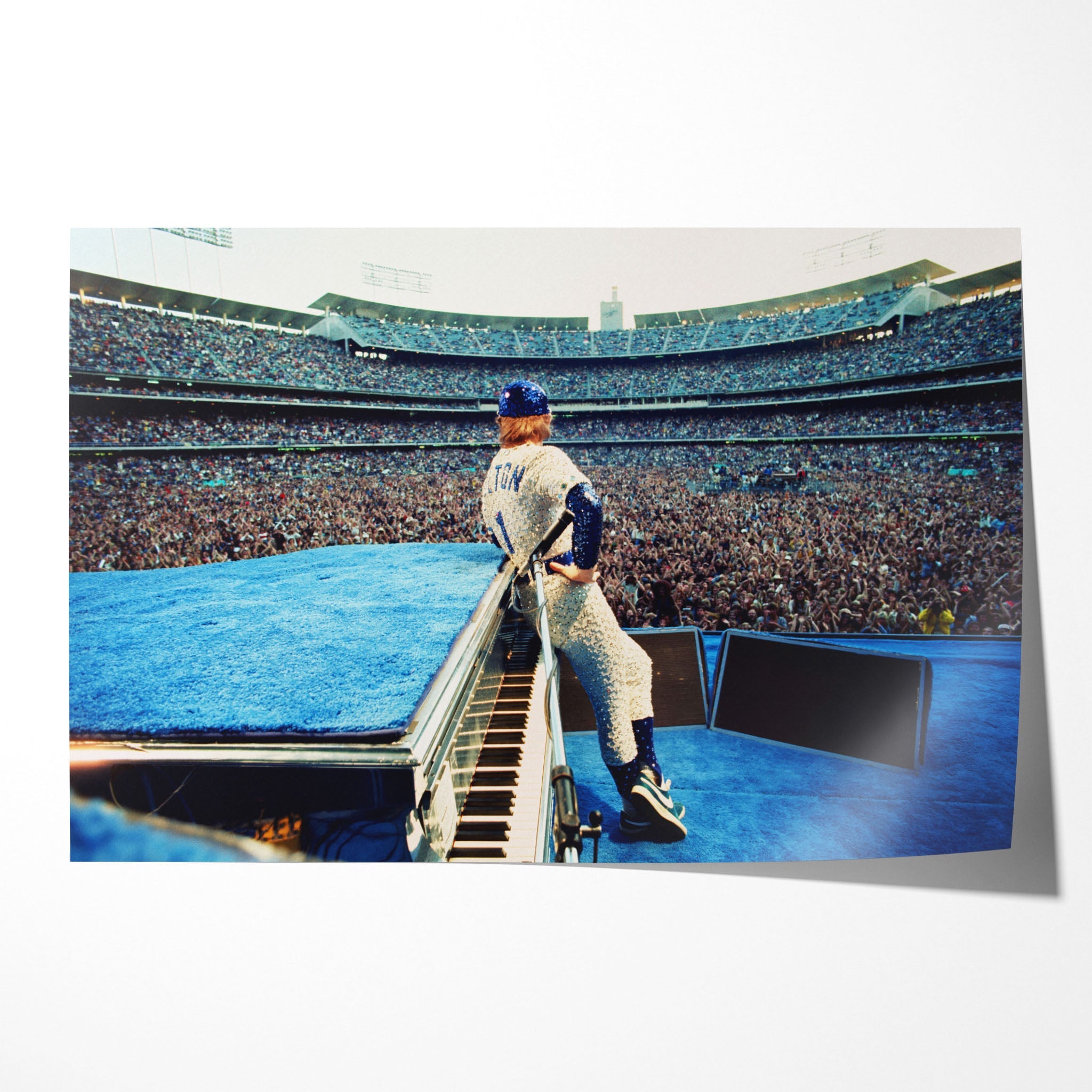 Unframed colour Elton John 1975 Dodger Stadium poster print in his sequined Dodgers uniform behind the blue piano before 100,000 fans.