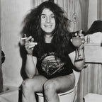 Zoomed detail of Ozzy Osbourne with his drink, cigarette and smiley-face knees in black and white, 1978