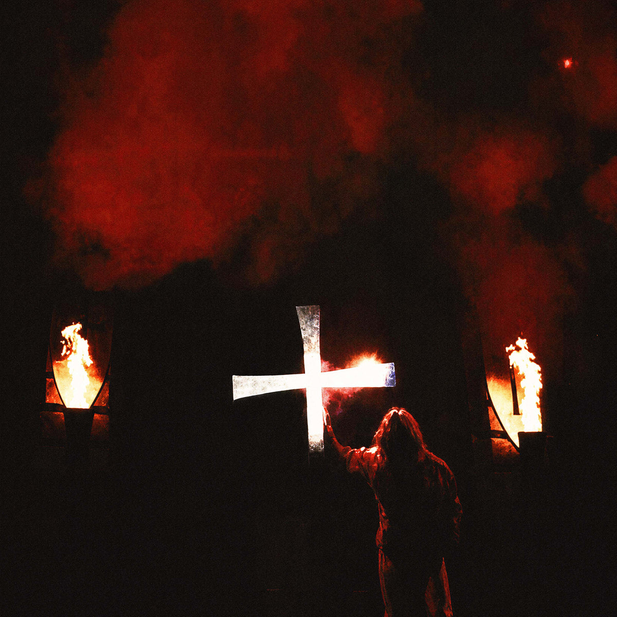 Zoomed detail of the blazing white cross and stage torches behind Ozzy Osbourne