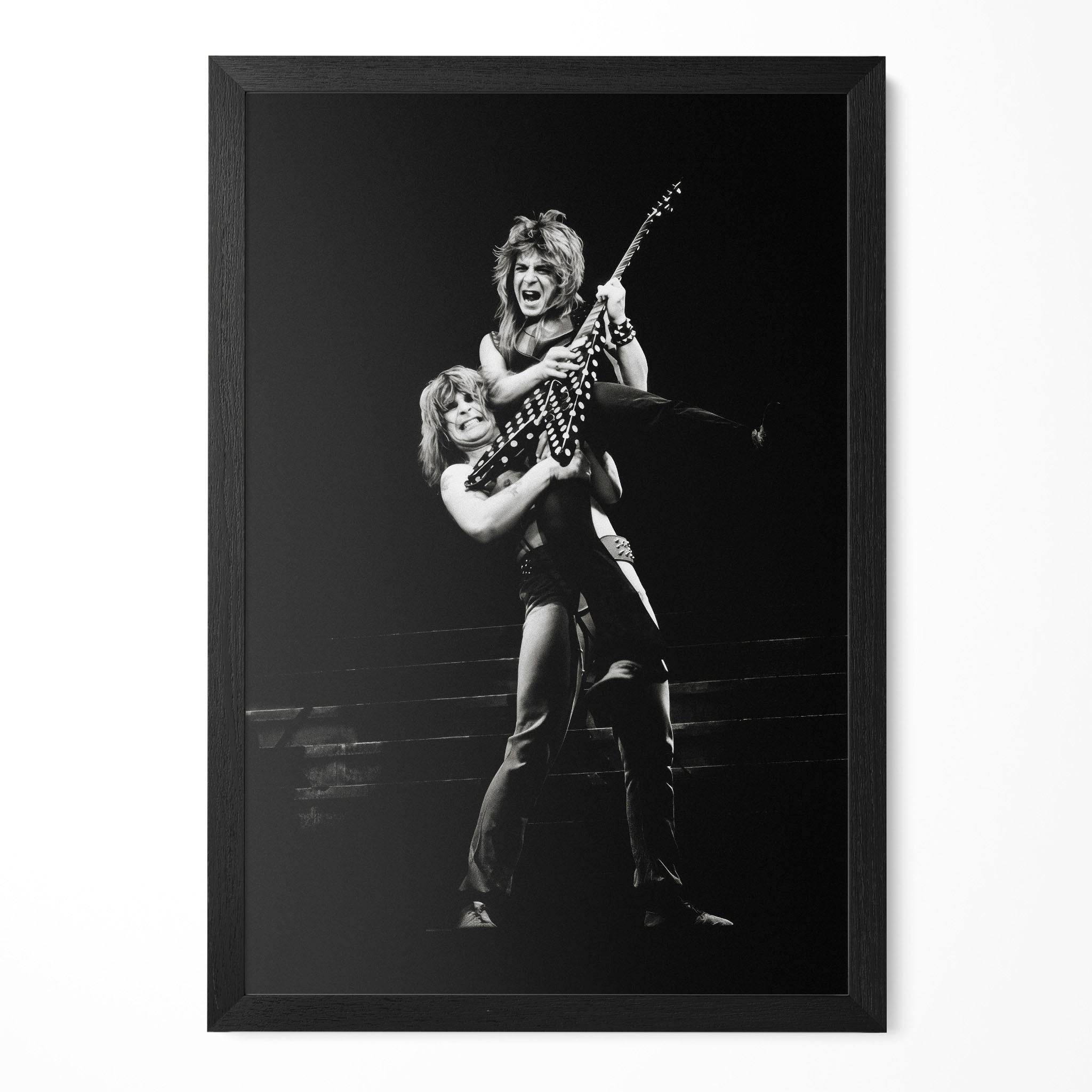 Ozzy Osbourne lifting Randy Rhoads on stage in 1982, black and white portrait in a classic black poster frame