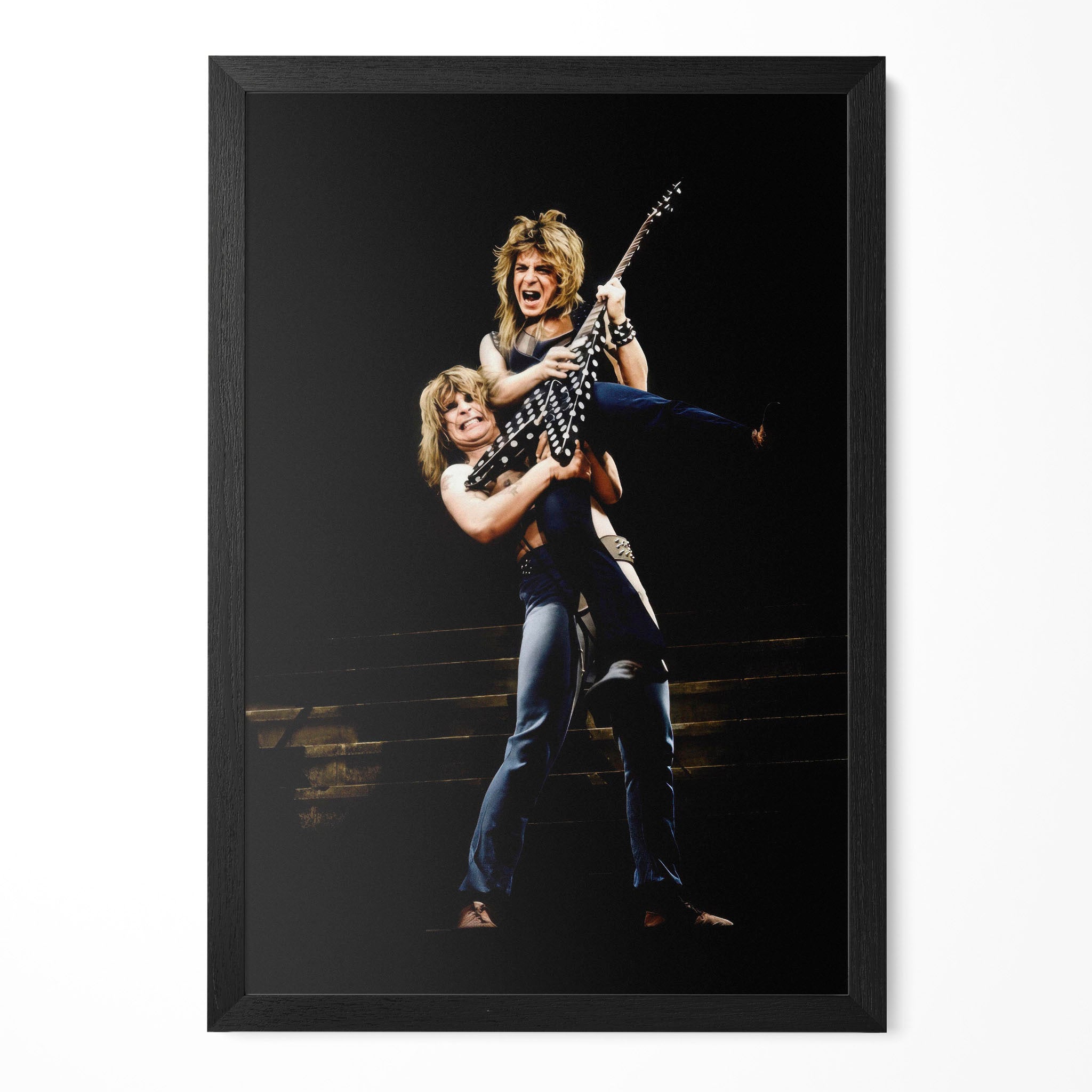 Ozzy Osbourne lifting Randy Rhoads on stage in 1982, colour portrait in a classic black poster frame